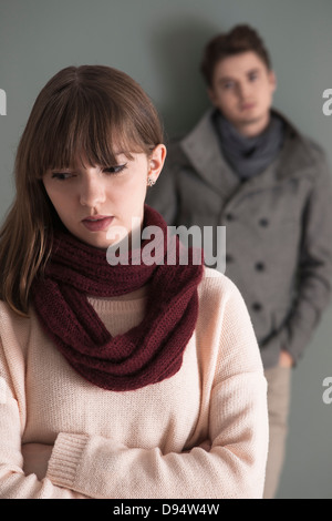 Porträt des jungen Mannes hinter junge Frau, sah sie intensiv, Studioaufnahme auf grauen Hintergrund Stockfoto