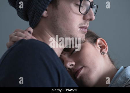 Close-up Portrait des jungen Paares zu umarmen, mit geschlossenen Augen, schoss Studio auf blauem Hintergrund Stockfoto