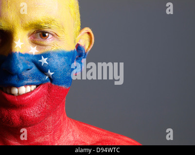 Mann-Gesicht mit venezolanischen Flagge gemalt. Der Mann lächelt und fotografischen Komposition lässt nur die Hälfte des Gesichts. Stockfoto