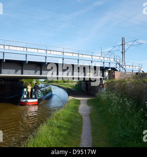 Schmale Boot unter Eisenbahnbrücke hindurch auf dem Trent und Mersey Kanal in der Nähe von Sandbach Cheshire UK Stockfoto