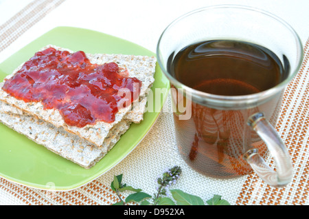 Cracker mit Erdbeermarmelade und Pfefferminztee Stockfoto