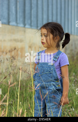 Kleine Mädchen tragen Overalls steht im Feld Stockfoto