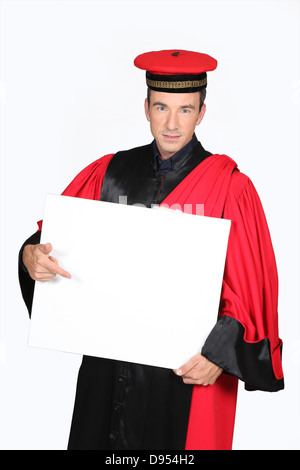 Mann in roten und schwarzen Gewand und Kappe zeigt am Brett leer für text Stockfoto