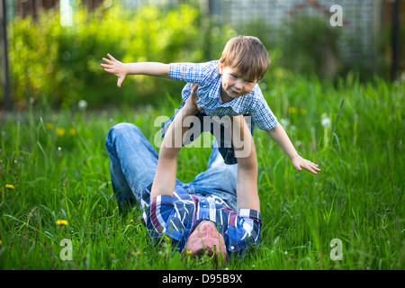 Vater und Sohn spielen liegen auf dem Rasen im park