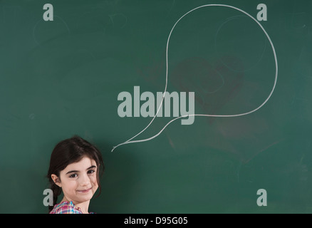 Mädchen vor der Tafel mit Sprechblase im Klassenzimmer Stockfoto