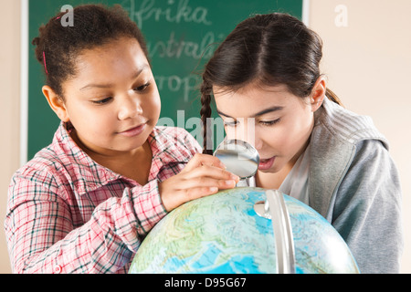 Porträt von Mädchen auf der Suche im Globe im Klassenzimmer, Baden-Württemberg, Deutschland Stockfoto