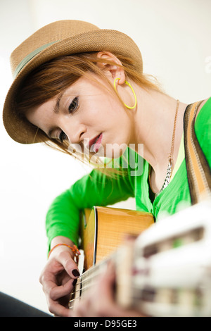 Close-up Portrait von Teenager-Mädchen tragen Hut und akustische Gitarre spielen, Studio gedreht auf weißem Hintergrund Stockfoto