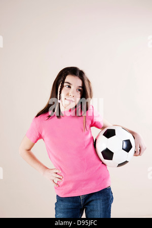 Porträt eines Mädchens mit Hand auf Hüften und hält Soccerball, Blick auf die Seite, Studioaufnahme Stockfoto