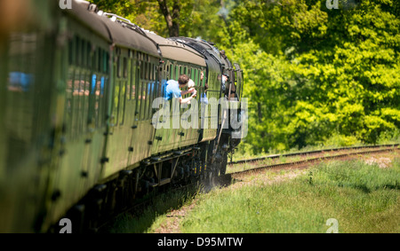 Volle Kraft voraus bei der Bluebell Railway in East Sussex, Großbritannien. Ein Zug, der sich direkt auf der ersten Dampfeisenbahn mit normaler Spurweite kurvt. Stockfoto