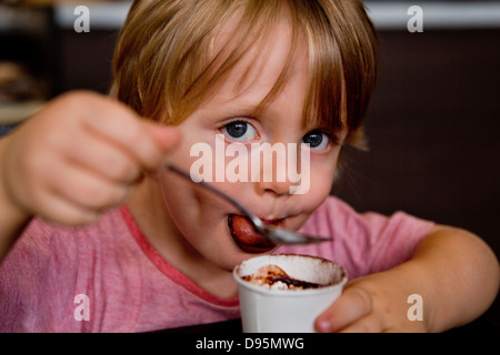 3 Jahre alter Junge Getränke warme Milch und Schokolade mit einem Löffel in einem café Stockfoto