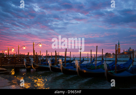 Romantische Aussicht auf Venedig mit Laternen und Gondeln am Piazza San Marco mit einem Sonnenaufgang und San Giorgio Maggiore. Stockfoto
