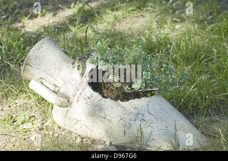 Antike Kanne mit Blumen auf dem grünen Rasen Stockfoto