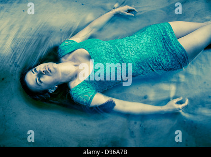 Frau im blauen Kleid, die im Wasser schweben Stockfoto