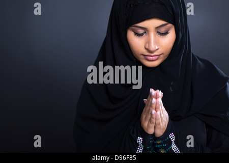 religiöse junge muslimische Frau beten auf schwarzem Hintergrund Stockfoto