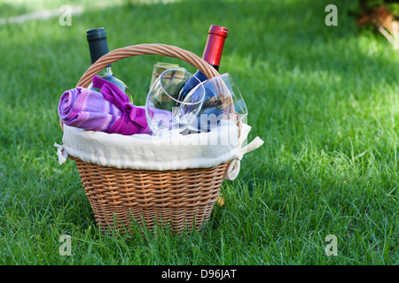 Outdoor-Picknick-Korb mit Wein in Flaschen und Gläser auf Rasen Stockfoto