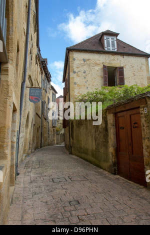 Holztür in Sandsteinwand entlang der Straße mit Kopfsteinpflaster in charmanten mittelalterlichen Stadt von Sarlat, Dordogne Region Frankreichs Stockfoto