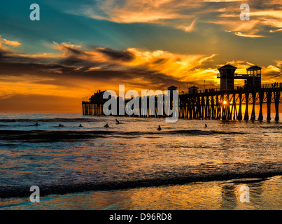 Geduld bei Sonnenuntergang - mehrere Surfer warten eine letzte Welle während einer anderen dramatischen Sonnenuntergang in der Nähe von Oceanside Pier in Südkalifornien. Stockfoto