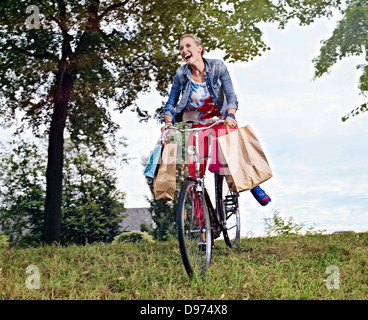 Deutschland, Köln, junge Frau auf dem Fahrrad mit Einkaufstüten Stockfoto