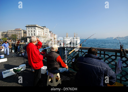 ISTANBUL, TÜRKEI. Angeln in das Goldene Horn von der Galata-Brücke, mit Karaköy Fährhafen und den Bosporus hinter. Stockfoto