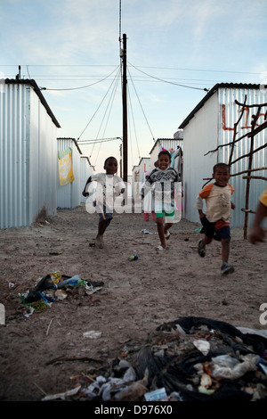 <p>Die Kinder Spesbona Hostel in Athlone spielen zwischen Wohneinheiten in Blikkiesdorp alle Familien Spesbona Hostel Stockfoto