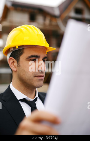 Junger Mann arbeitet als Ingenieur in neue Wohnblocks, Blick auf Bauplan in Baustelle Stockfoto