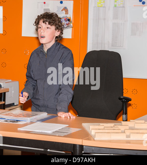 Junge stand hinter dem Schreibtisch im Klassenzimmer Stockfoto