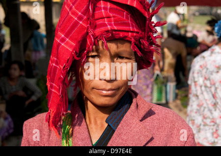 PA-O Frau trägt einen roten aufgegebenen Kopfschmuck, schaut in die Kamera in einem Markt, Myanmar (Burma) Stockfoto