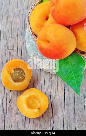 Aprikose Früchte mit grünen Blatt und Schnitt auf hölzernen Hintergrund isoliert Stockfoto