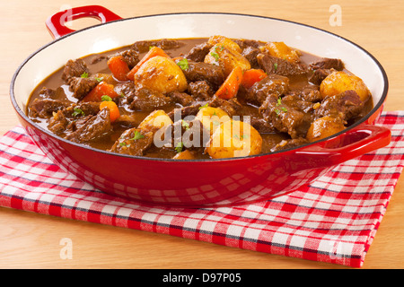 Eintopf mit Möhren und Kartoffeln - einen einfachen Eintopf in einem roten Topf mit Möhren und Kartoffeln. Stockfoto