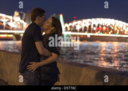 Kaukasische Liebespaar küssen auf einem Granit-Damm gegenüber Bolscheochtinsky Brücke in St. Petersburg. Weiße Nächte Zeitraum Stockfoto