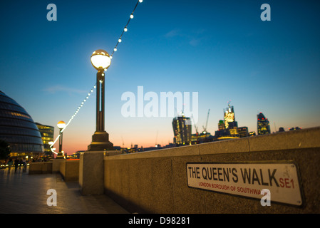 LONDON, Großbritannien – The Queens Walk im Londoner Stadtteil Southwark, in der Nähe der Tower Bridge, bei Dämmerung, mit den Lichtern der Innenstadt von London im Hintergrund. Stockfoto