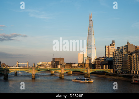 Die Shard London Skyline von Millennium Bridge London // LONDON, Großbritannien - Ein Panoramablick auf die Londoner Skyline von der Millennium Bridge nach Osten. Die Southwark Bridge überspannt die Themse im Vordergrund, während die berühmte Tower Bridge in der Ferne links zu sehen ist. Das Shard, Londons höchstes Gebäude, dominiert die Skyline mit seiner charakteristischen kantigen Form. Stockfoto