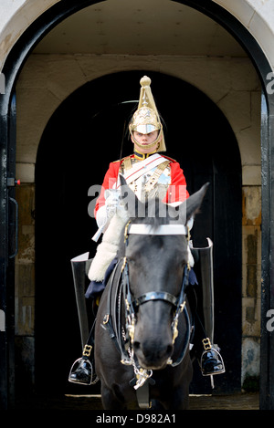 Life Guards Household Cavalry Whitehall London | LONDON, Vereinigtes Königreich — Ein Life-Guards-Trupp auf einem schwarzen Pferd hält unter dem Torbogen bei Horse Guards, Whitehall, Wache. Der gefederte Helm und die scharlachrote Uniform kennzeichnen das Senior-Regiment der Household Cavalry, das seit 1660 abwechselnd mit den blau uniformierten Blues and Royals die zeremonielle Wache über den Souverän hält. Stockfoto