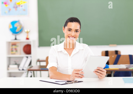 schöne weibliche Lehrer halten einen Tabletcomputer im Klassenzimmer Stockfoto