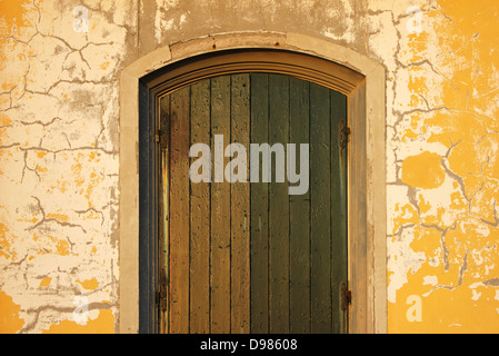 Gerader Schlag von eine alte Eingangstür mit Rusty Scharniere und Risse an der Wand. Stockfoto