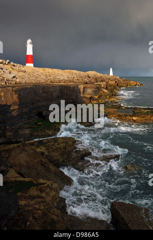 Portland Bill Leuchtturm in Dorset mit der Einstellung Sonne leuchten die Gebäude gegen die eingehenden dunkle Gewitterwolken. Stockfoto