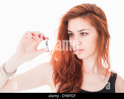 Junge rote kurzhaarige Frau in ihren 20ern halten Miniatur Figur des Kaufmanns. Stockfoto