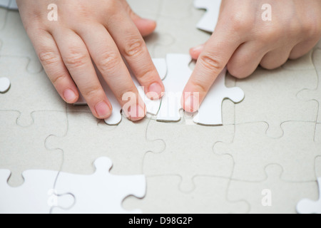 Hände des kleinen Mädchens 3-4 Jahre Platzierung weiß Puzzleteile Stockfoto