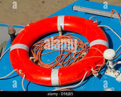 Bunte orange Rettungsring und Seil auf einem kleinen Boot. Stockfoto