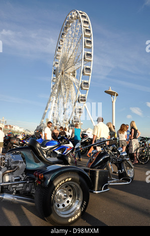 Motorräder und Menschen auf der Promenade, mit den Brighton Rad im Hintergrund, an einem warmen, sonnigen Tag im Frühherbst. Südküste von England, UK. Stockfoto