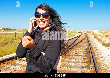 Junge schöne Frau ist an einem Bahngleis telefonieren. Stockfoto
