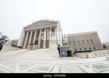 Renovierung des Supreme Court-Gebäudes Washington DC | WASHINGTON D.C., Vereinigte Staaten — Gerüste erheben sich über dem Giebeldach des Gebäudes des Obersten Gerichtshofs der Vereinigten Staaten, während ein provisorisches Dach einen Seiteneingang während der Außenrestaurierungsarbeiten abdeckt. Die sitzende Marmorfigur der „Kontemplation der Gerechtigkeit“ blickt von ihrem Sockel neben der verhüllten Kolonnade aus, eine von zwei allegorischen Skulpturen, die die Stufen des Gerichtsgebäudes flankieren. Stockfoto