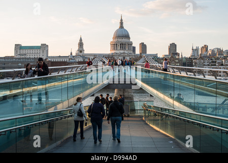Millennium Bridge mit St Pauls Cathedral London England / LONDON, England – Fußgänger gehen über die Millennium Bridge, eine Stahlbrücke, die die Themse überspannt, mit der Kuppel der St. Paul's Cathedral in der Ferne. Die heutige Kathedrale, die von Sir Christopher Wren entworfen wurde, wurde zwischen 1675 und 1710 nach dem Großen Brand von London an einem Ort errichtet, an dem seit 604 n. Chr. eine Kirche untergebracht ist. Die Millennium Bridge wurde 2000 als Londons erste neue Thames-Kreuzung seit über einem Jahrhundert eröffnet und verbindet die City of London mit Tate Modern und Shakespeare's Globe am South Bank. Stockfoto