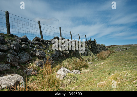 Eine alte krumme Trockenmauer, mit einem Zaun auf dem oberen ausdehnen in die Ferne Stockfoto