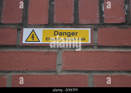 Schild Warnung vor "Danger - Stromschlag-Gefahr" auf einer Mauer montiert. Stockfoto