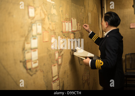 LONDON, Vereinigtes Königreich – Ein Manequin eines Militärs, der eine der großen Wandkarten im Kartenraum der Churchill war Rooms in London aktualisiert. Das Museum, einer von fünf Zweigen des Imerial war Museums, beherbergt den Untergrundbunker des Zweiten Weltkriegs, den der britische Premierminister Winston Churchill benutzt hat. Die beengten Quartiere wurden aus einem umgebauten Lagerkeller im Treasury Building in Whitehall, London, errichtet. Die unterirdischen Kabinettsräume und unter einem ungewöhnlich robusten Gebäude wurden vor den Bomben geschützt, die während des Blitz fielen. Stockfoto