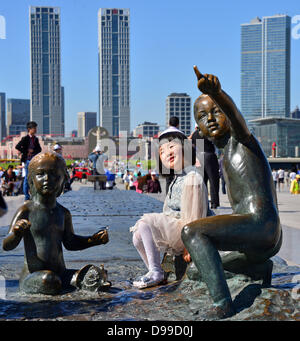 Ein kleines Mädchen steht auf einer Skulptur vor der Skyline von Dalian, China, 29. Mai 2013. Thüringens Ministerpräsident besucht China mit einer großen Delegation bis zum 31. Mai. Gespräche und Begegnungen sollte die wirtschaftlichen und wissenschaftlichen Beziehungen gestärkt und ausgebaut werden. Foto: MARTIN SCHUTT Stockfoto