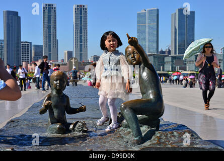 Ein kleines Mädchen steht auf einer Skulptur vor der Skyline von Dalian, China, 29. Mai 2013. Thüringens Ministerpräsident besucht China mit einer großen Delegation bis zum 31. Mai. Gespräche und Begegnungen sollte die wirtschaftlichen und wissenschaftlichen Beziehungen gestärkt und ausgebaut werden. Foto: MARTIN SCHUTT Stockfoto