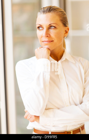 nachdenklich weibliche senior Büroangestellter vor Fenster suchen Stockfoto