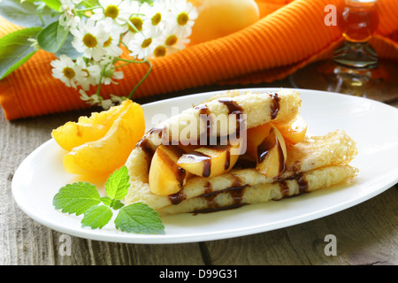 dünne Pfannkuchen (Crepes) mit Pfirsichen und Schokoladensauce Stockfoto